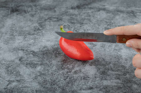 A whole fresh red pepper on a gray background
