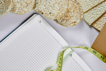 Rice crackers, notebook, and tape measure on a white backgroundの写真素材
