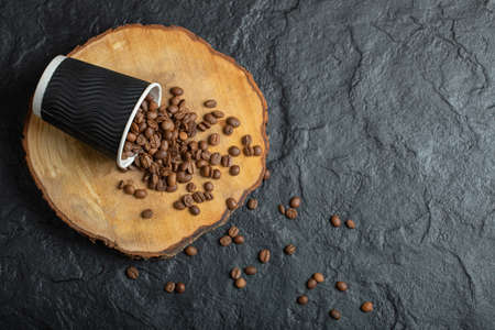 A black cup full of coffee beans on a wooden boardの写真素材