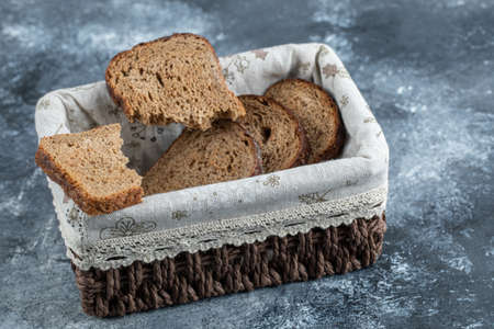 Slices of brown bread on a basket on a gray background