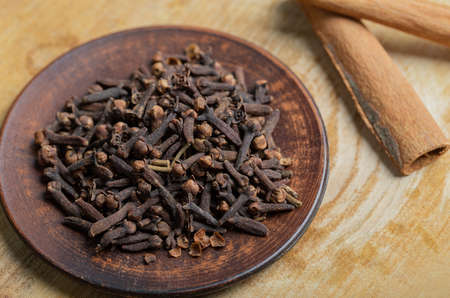 A brown plate full of dried cloves on a wooden table