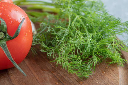 Three fresh tomatoes with greens on a wooden boardの写真素材