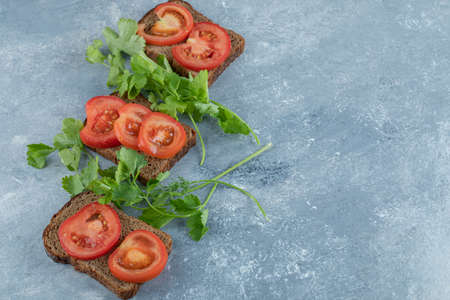 Delicious toasts with slices of tomato on a gray background