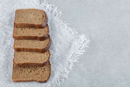Slices of brown bread on white burlapの写真素材