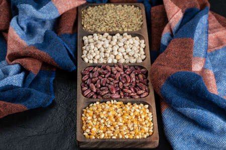 Wooden plates with raw beans and popcorn on a dark backgroundの写真素材