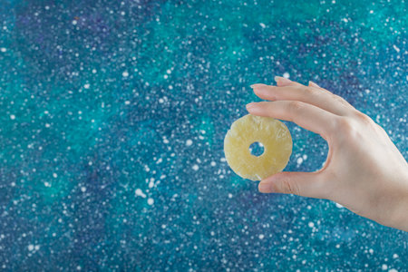 Woman hand holding a slice of dried pineappleの写真素材