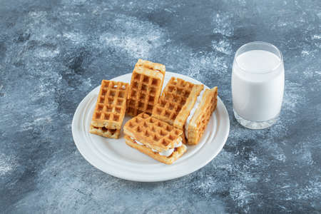 Plate of waffles and glass of milk on marble surface