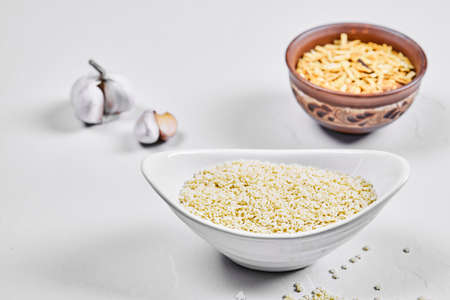 Two bowls of raw pastas with garlic on white backgroundの写真素材