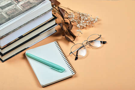 Books, notebook, pen and glasses on orange backgroundの写真素材