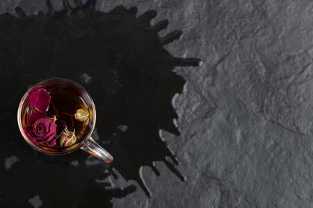 Dried rose in a cup of hot tea on a black backgroundの写真素材