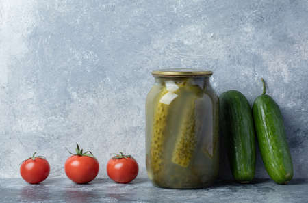 Cucumbers pickled in a glass jar on a marble background
