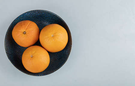 A black plate full of orange fruits on a white backgroundの写真素材