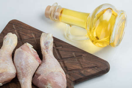 Close up photo of raw chicken legs with bottle of oil