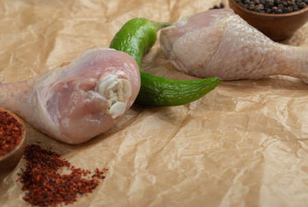 Raw chicken drumsticks with pepper on food paper. Close upの写真素材