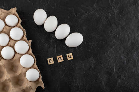 Cardboard egg box with white chicken eggs on a black backgroundの写真素材
