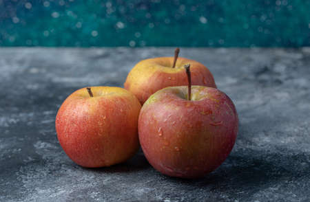 Three fresh red apples on a marble background
