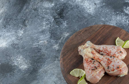 Marinated raw chicken legs on wooden board over grey backgroundの写真素材