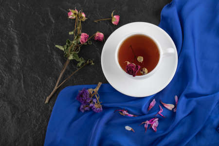 Dried roses with a cup of hot tea on a black backgroundの写真素材
