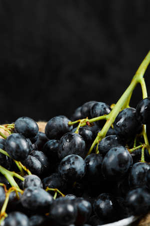 A cluster of black grapes in a bucket on dark background, close upの写真素材