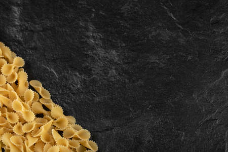 Many raw farfalle tonde on a black background