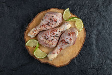 Raw chicken drumsticks on wooden board