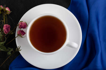 Dried roses with a cup of hot tea on a black backgroundの写真素材
