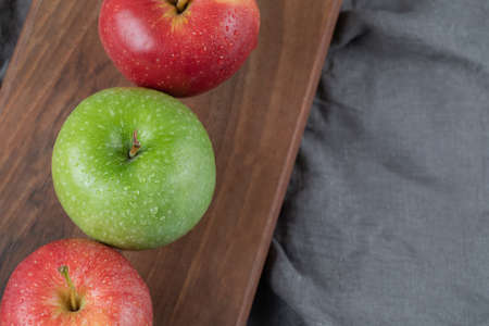 Red and green apples in a row on a wooden boardの写真素材