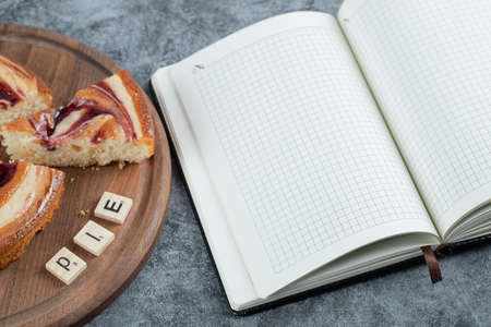 Strawberry pie on a wooden board with a recipe book aside