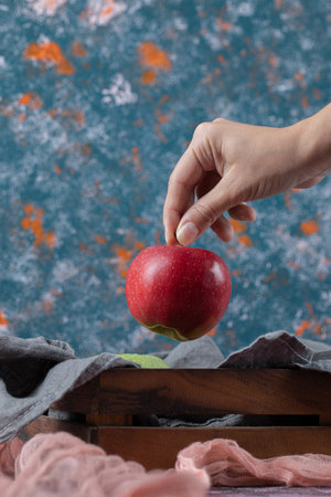Apples in a wooden tray on the grey towelの写真素材