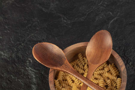 A wooden bowl full of raw girandole pastaの写真素材