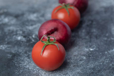 Purple onions with red fresh tomatoes on marble backgroundの写真素材