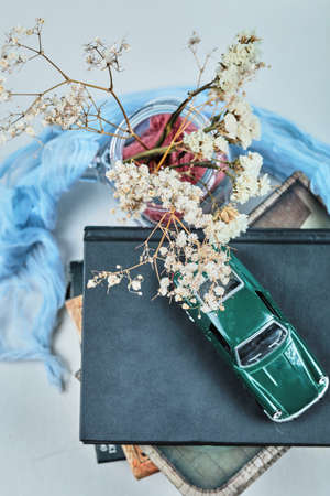 A tiny car on the top of books with jar of flowersの写真素材