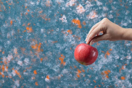 Farmer holding a red apple on blue backgroundの写真素材
