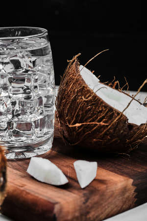 Half cut coconut on wooden board and glass of water with iceの写真素材