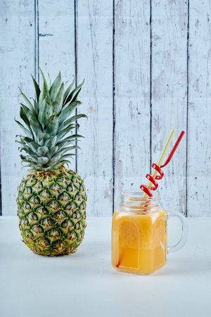 Ripe pineapple and a glass of juice on blue backgroundの写真素材