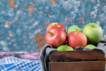 Red and green apples in a wooden containerの写真素材