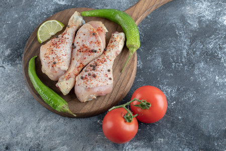 Raw spicy chicken drumsticks with green pepper and tomatoes top viewの写真素材