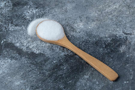 Salt in a wooden spoon on a marble backgroundの写真素材