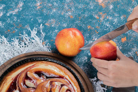 Strawberry pie on a wooden board with peaches around