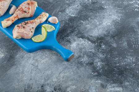 Spicy raw chicken legs over blue wooden board. Top view