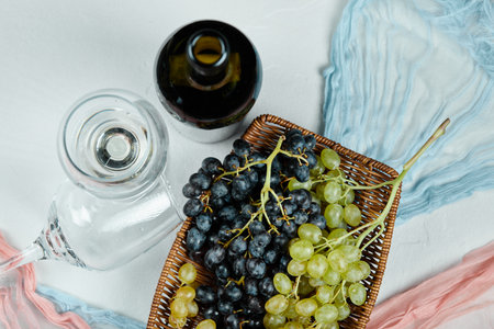 A cluster of mixed grapes in basket and glasses of wine and bottleの写真素材