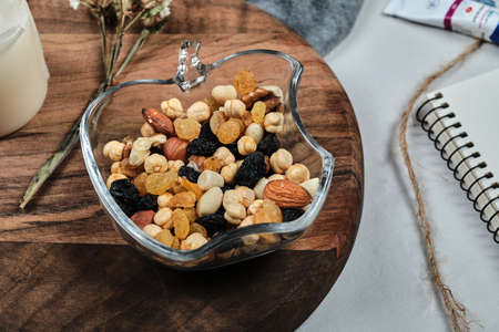 A plate of nuts with candle, flower, paper and tubes on the wooden boardの写真素材