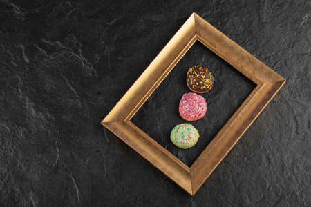 Sweet small doughnuts with sprinkles on a black background