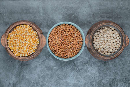 Different kinds of uncooked beans and corns in various potsの写真素材