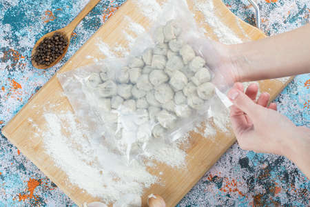 Female hands holding pocket of dumpling on top of wooden boardの写真素材