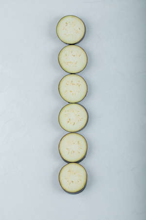 Sliced raw eggplants in a row on white backgroundの写真素材