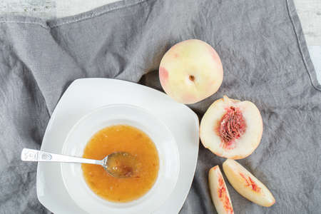 A white plate full of peach jam and spoonの写真素材