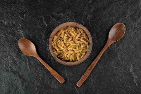A wooden bowl full of raw girandole pastaの写真素材