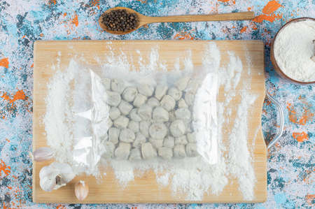 Raw dumplings with flour on a wooden boardの写真素材