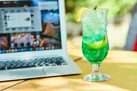 A fruit lemonade next to laptop on wooden tableの写真素材